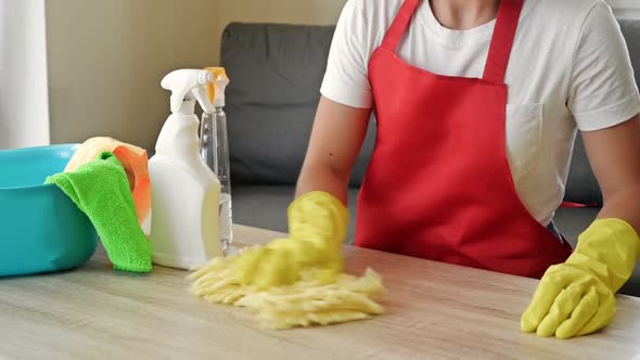 Woman in an Apron and Protective Gloves Washes and Polishes the Countertop Diligently