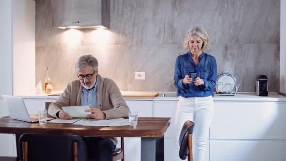 Slow motion shot of mature man with papers, woman using smartphone