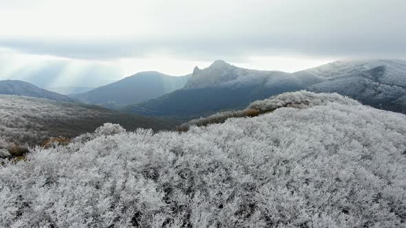 A Mountain Landscape From the Perspective of Forests Covered with Frost Under a Cloudy Sky Through