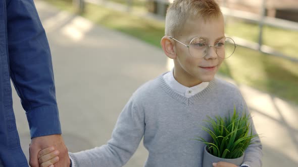 Close View of the Father Holding Sons Hand and Son is Holding the Plant in a Pot Telling Father How