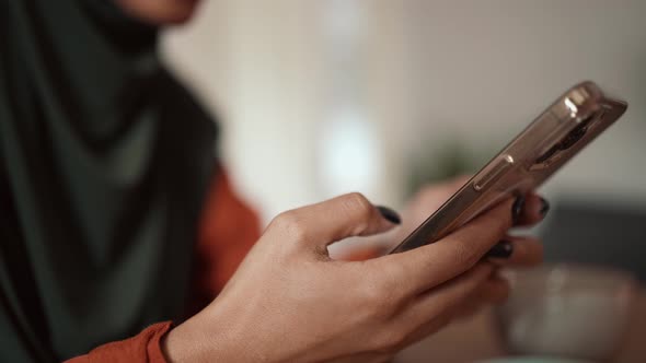 Muslim woman typing by phone