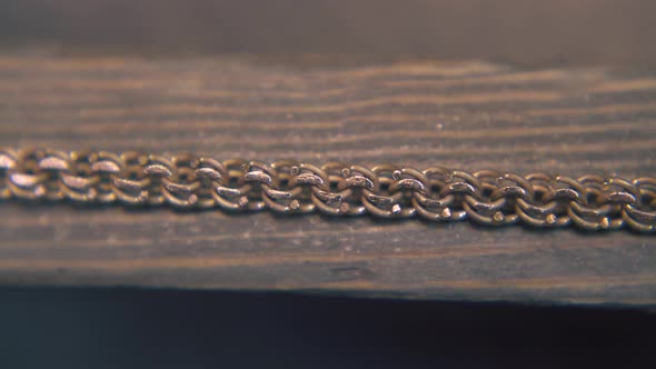 Goldsmith Grinds Chain with Rasp on Wooden Gutter Close View