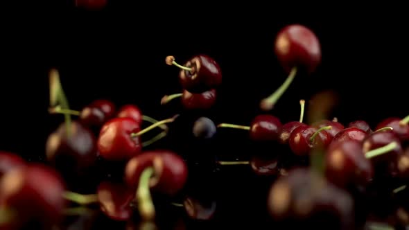 A handful of bright red cherries dropped onto black surface