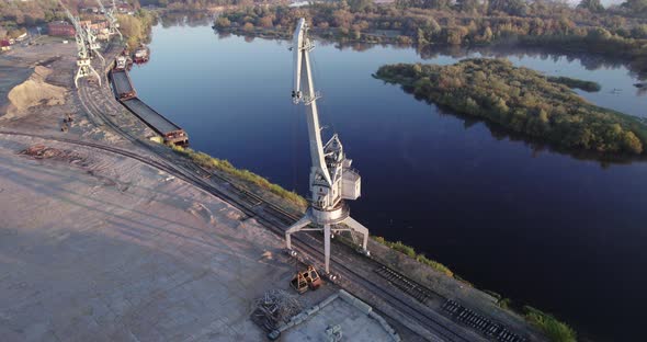 Boom of an Idle Port Crane on the Background of the River at Dawn