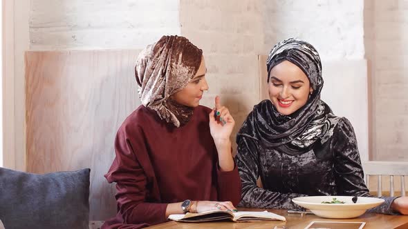 Two Young Beautiful Muslim Business Women in Hijab Working with Documents in Cafe.