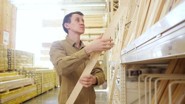 Young Man Client Checks Wooden Board Near Shelf in Store