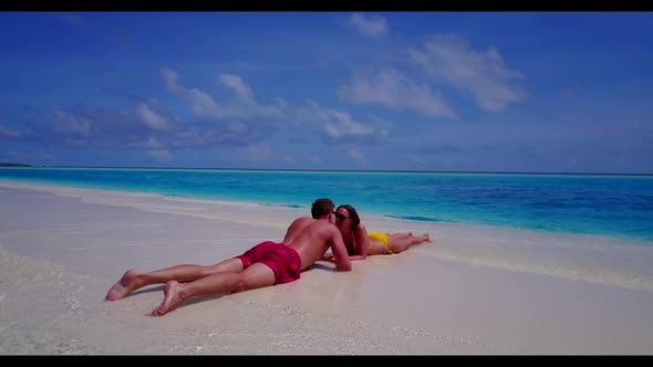 Romantic couple tanning on luxury bay beach trip by transparent lagoon with white sand background of