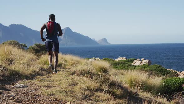 African american man cross country running in countryside by the coast