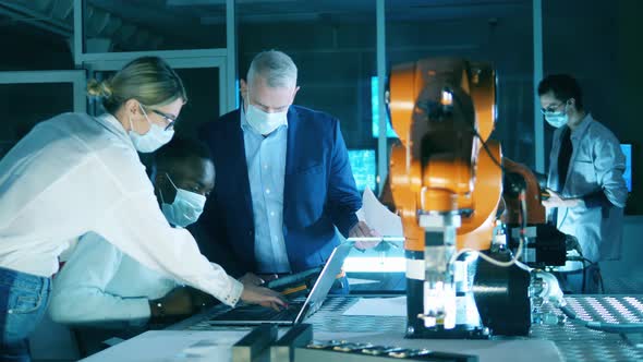 Researchers in Face Masks Are Talking in the Robotics Laboratory