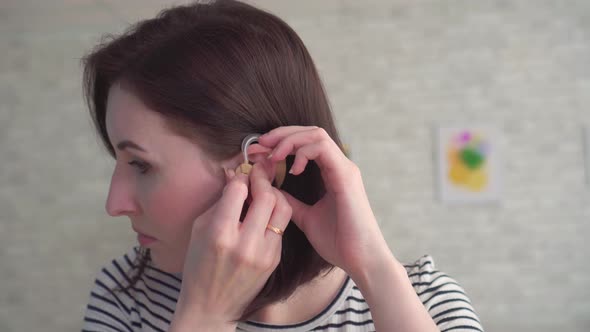  Young Woman Inserts a Hearing Aid Into Her Ear