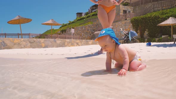 For the First Time, a Child Near the Ocean with His Mother Touches Salt Water 