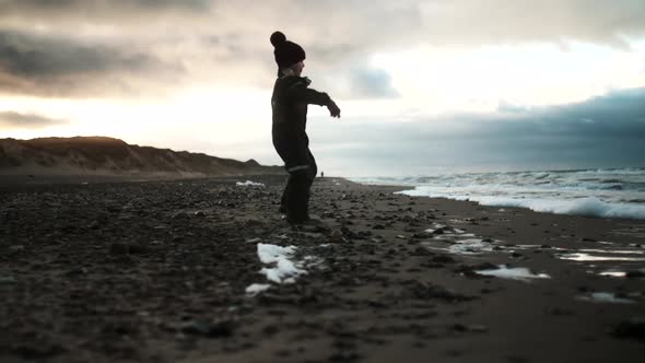 Girl Throwing Pebble On Beach Into Sea