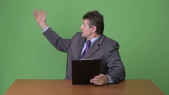 Mature Handsome Businessman Against Green Background