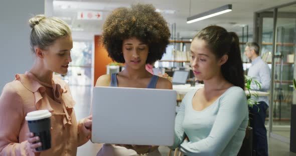 Diverse female business colleagues talking and using laptop