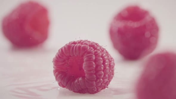 Raspberry Falls Down on Heap of Fresh Berries with Water Drops Slow Motion