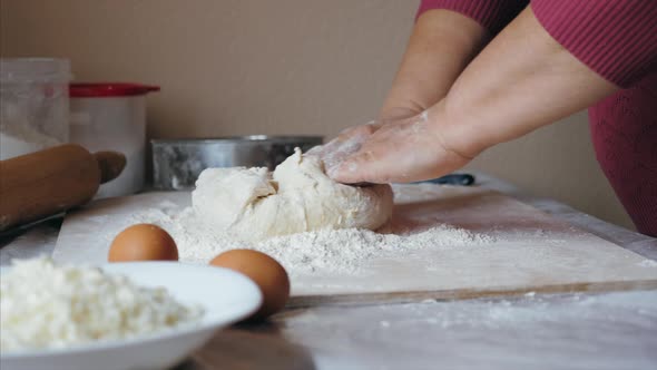 Closeup Hands of Senior Female is Kneading a Dough at Home Kitchen Side View