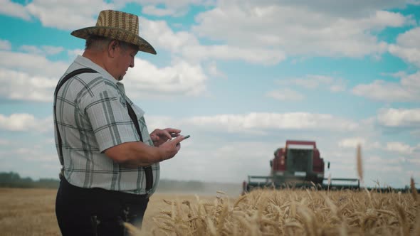 Senior Farmer Standing in a Wheat Field Using Modern Technologies in Agriculture Against 