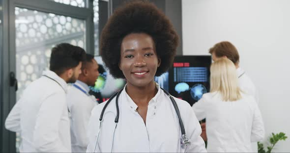 Black-Skinned Doctor with African Hairstyle Poses on Camera