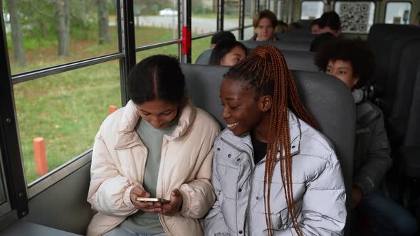 Joyful Multiracial Girls Using Phone on School Bus