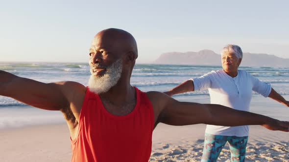 Senior african american couple practising yoga at the beach