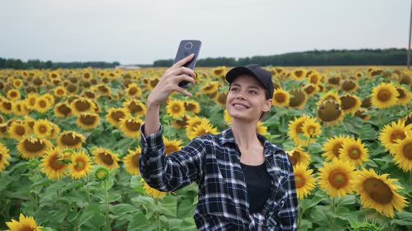 Countryside Woman Farmer Standing in a Field of Sunflowers and Takes Selfie Pictures on a Smartphone