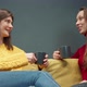 Two Smiling Girls Discuss Gossip Sitting on Cozy Yellow Sofa Drinking Coffee - VideoHive Item for Sale