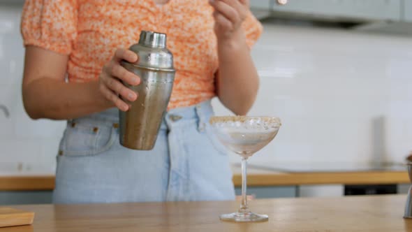 Woman with Shaker Pouring Cocktail Drink to Glass