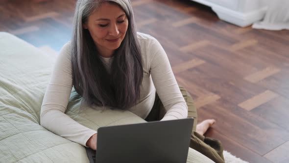 Asian woman typing by laptop