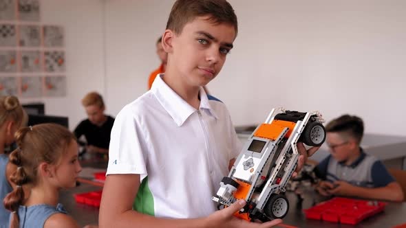 Portrait of a Smart Boy in a Robotics Class at School Holding a Robot