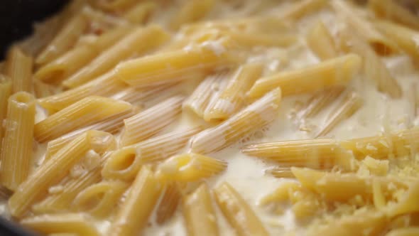 Cook adding cheese to creamy pasta