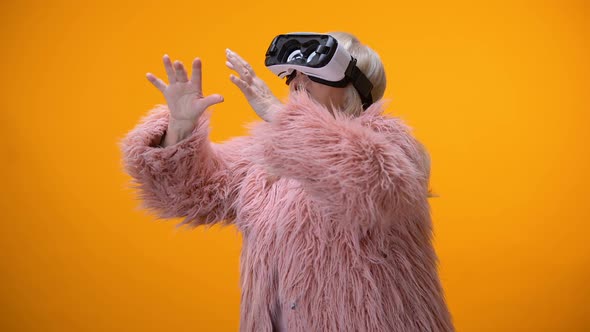 Senior Woman in Funny Coat and VR Headset Playing Video Game, Hi-End Innovations