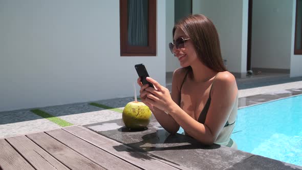 Woman Is Resting in Pool Using Smartphone