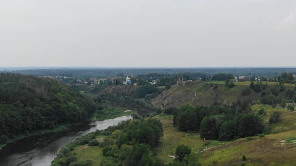 Aerial View of River in Eastern Europe With Castle and Small Village in Background With Birds Flying