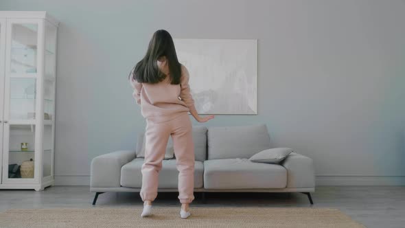 Crazy young Caucasian woman making funny moves and dancing funny at home.