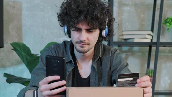 Young Man Shopping Online with Credit Card Using Smart Phone at Home