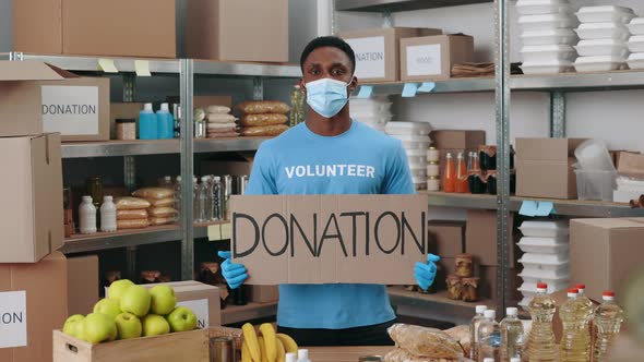 African American Man in Face Mask and Gloves Holding Donation Banner