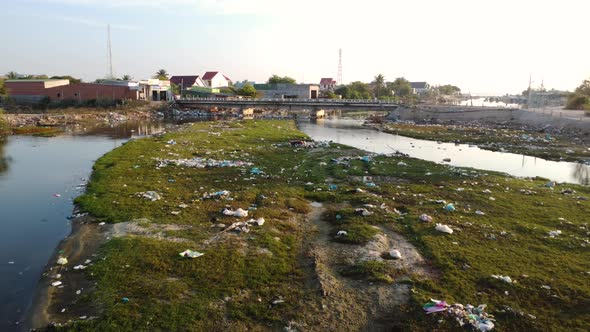 Scene with garbage on bank of polluted river, Vietnam. Aerial flying forward