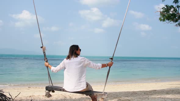 A Young Woman Swinging on a Swing on the Beach