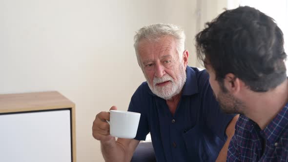 The elderly father and son morning conversation with a cup of coffee at home.