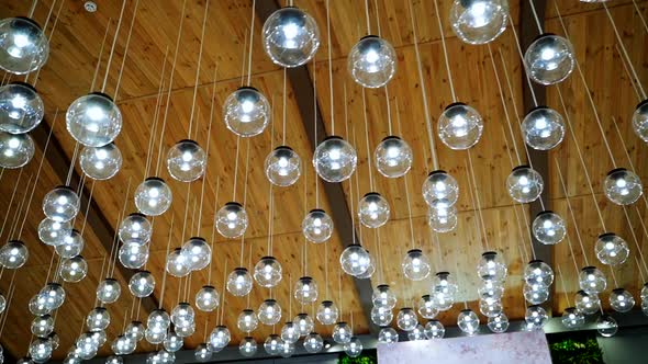 Creative interior of many lamps. Modern ceiling lighting of hanging light bulbs indoors.