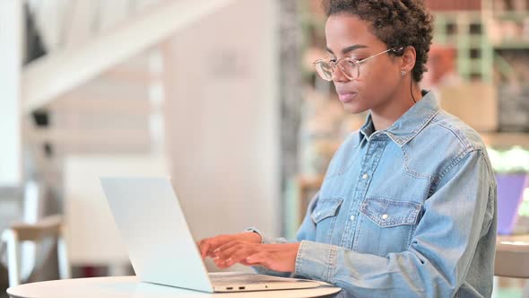 African Woman Working on Laptop at Cafe