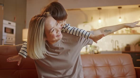 Happy Young Asian Mommy Playing with Cute Small Adorable Toddler Child Son Up Having Fun Fly in Mum