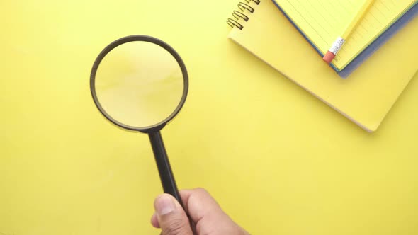 Hand Holding Magnifying Glass on Yellow Background