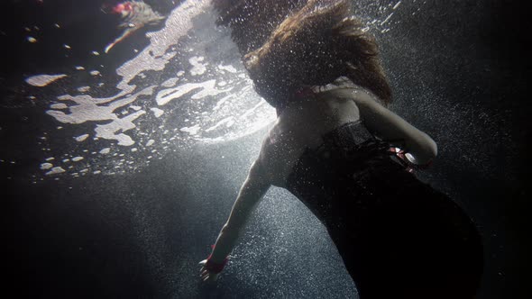 A Woman in a Black Suit Floats Under the Water Her Long Hair Flying