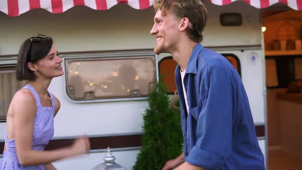 Smiling Couple Man and Woman Having Fun Time Together Dancing Together Near House on Wheels Outdoors