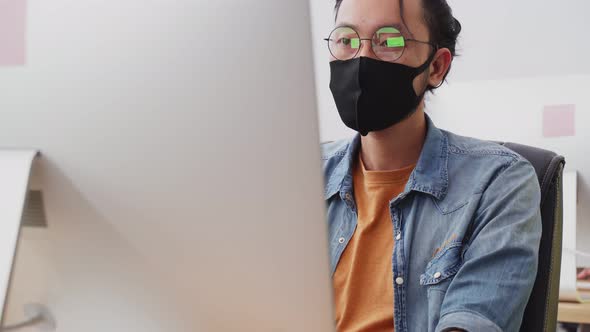 Asian young businessman wear face mask and working on computer in office with new normal lifestyle.