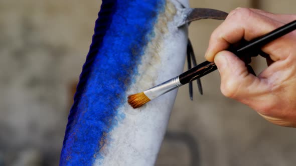 Craftsman polishing fish sculpture in workshop 4k