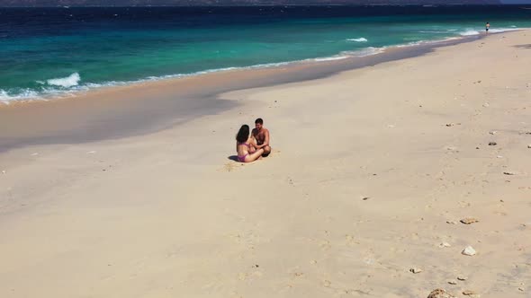 Boy and girl tanning on marine seashore beach voyage by blue lagoon with white sand background of Ba