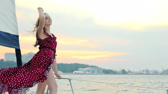 Girl in an Evening Dress Stands on a Yacht at Sunset