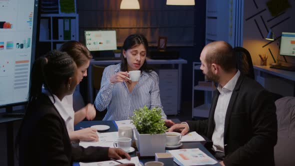 Businesswoman Holding Cup of Coffee While Discussing with Multiethnic Teamwork